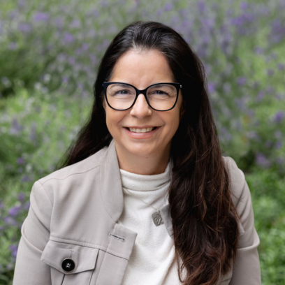 Headshot of Cassandra McGarvie, a smilley women with brown hair and black framed glasses